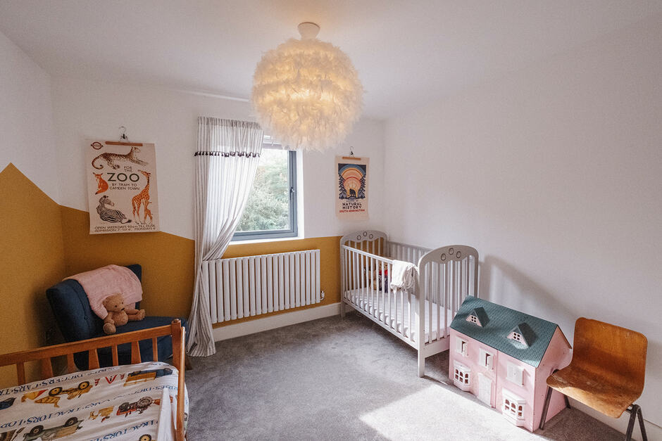 A child's bedroom with a cot and doll's house.