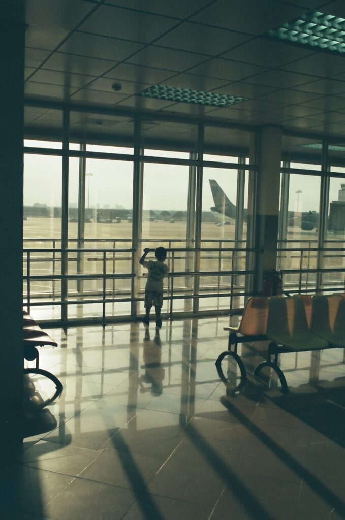 A child looking out at a plane at take off.